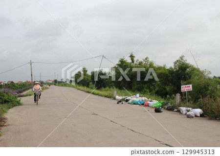 rural road in vietnam with people riding bicycles and motorbikes rural road in vietnam with people riding bicycles and motorbikes 129945313