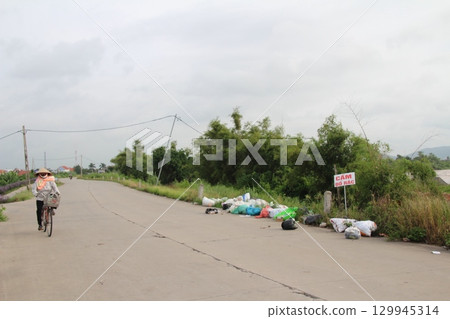 rural road in vietnam with people riding bicycles and motorbikes rural road in vietnam with people riding bicycles and motorbikes 129945314