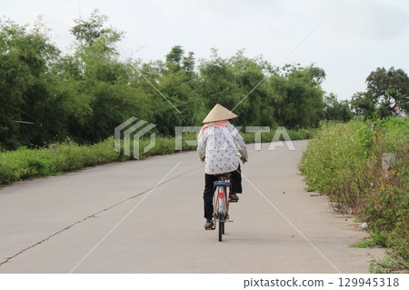 rural road in vietnam with people riding bicycles and motorbikes rural road in vietnam with people riding bicycles and motorbikes 129945318