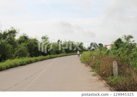rural road in vietnam with people riding bicycles and motorbikes rural road in vietnam with people riding bicycles and motorbikes 129945325