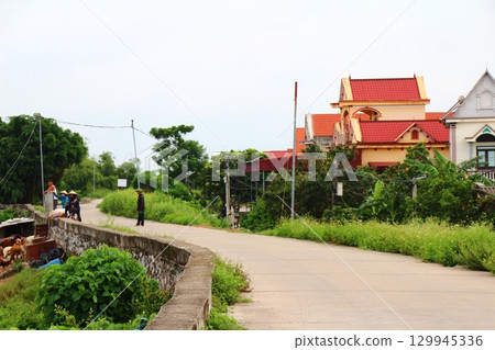 rural road in vietnam with people riding bicycles and motorbikes 129945336