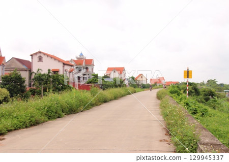 rural road in vietnam with people riding bicycles and motorbikes 129945337