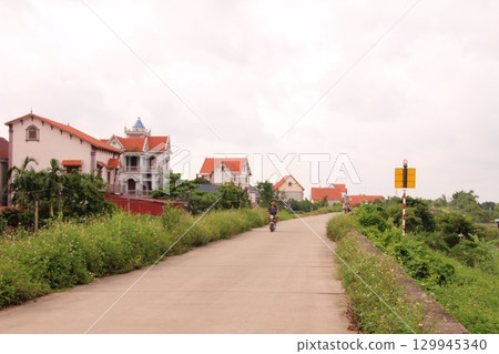 rural road in vietnam with people riding bicycles and motorbikes rural road in vietnam with people riding bicycles and motorbikes 129945340