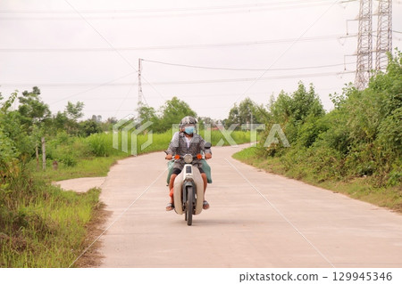 rural road in vietnam with people riding bicycles and motorbikes 129945346