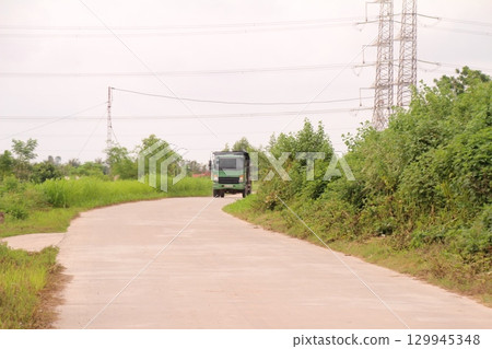 rural road in vietnam with people riding bicycles and motorbikes 129945348