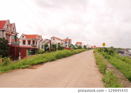 rural road in vietnam with people riding bicycles and motorbikes rural road in vietnam with people riding bicycles and motorbikes 129945435