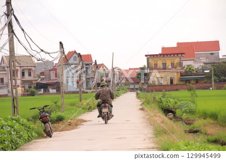 rural road in vietnam with people riding bicycles and motorbikes rural road in vietnam with people riding bicycles and motorbikes 129945499