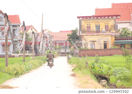 rural road in vietnam with people riding bicycles and motorbikes rural road in vietnam with people riding bicycles and motorbikes 129945502