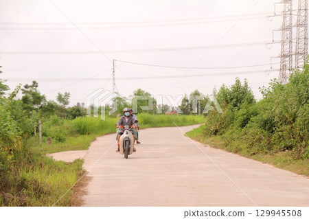 rural road in vietnam with people riding bicycles and motorbikes 129945508