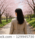 Rear view of a woman walking along a row of cherry trees 129945730