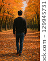 Back view of a man walking through a forest of autumn leaves 129945731