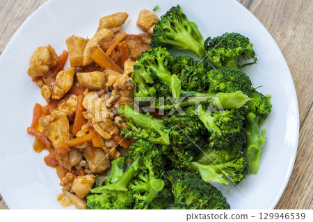 Cooked broccoli and chicken breast on the plate. Cooked broccoli and chicken breast on the plate. 129946539