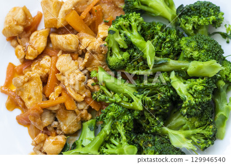 Cooked broccoli and chicken breast on the plate. 129946540