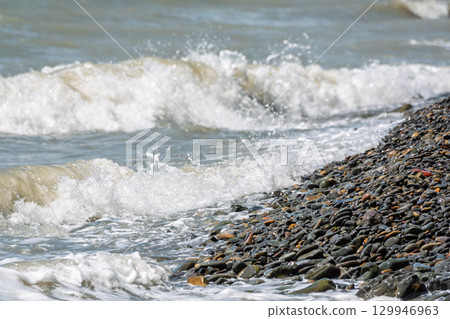 Sea water splashing over the stones on the beach Sea water splashing over the stones on the beach 129946963
