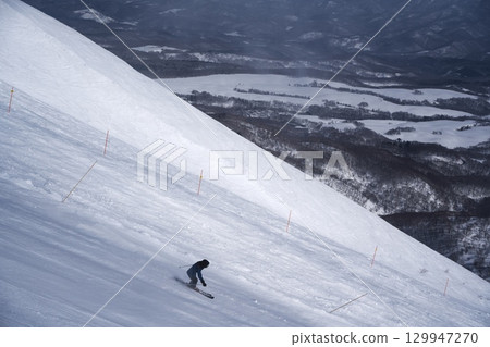 Skiers skiing down the dynamic course at Niseko Tokyu Grand Hirafu 129947270