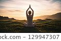 Serene woman in silhouette practicing yoga and meditation on a grassy cliff overlooking the ocean 129947307