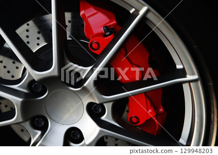 Sports car wheel and red brake caliper 129948203