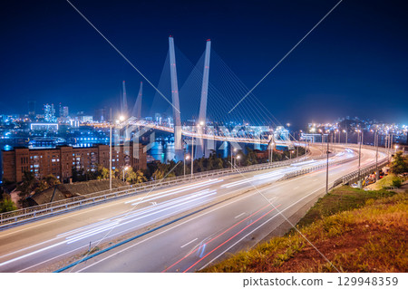 The zolotoy bridge in vladivostok, russia, shines brightly at night, with light trails from cars adding dynamism to the urban landscape The zolotoy bridge in vladivostok, russia, shines brightly at night, with light trails from cars adding dynamism to the urban landscape 129948359