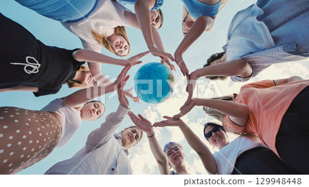 School friends uniting to protect the environment and promote global sustainability by joining hands around a globe School friends uniting to protect the environment and promote global sustainability by joining hands around a globe 129948448