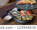 Charcoal grilled seafood platter with a variety of shellfish including shrimp, clams, mussels, and squid, cooked over open flame. 129948636