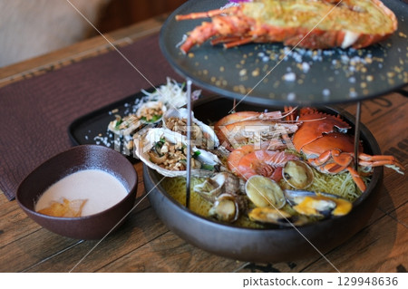 Charcoal grilled seafood platter with a variety of shellfish including shrimp, clams, mussels, and squid, cooked over open flame. Charcoal grilled seafood platter with a variety of shellfish including shrimp, clams, mussels, and squid, cooked over open flame. 129948636
