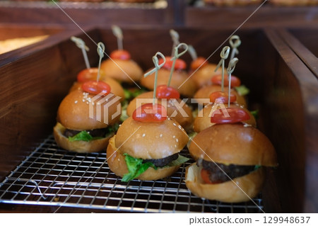 mini burgers with cheese and lettuce with sticks on a wooden background mini burgers with cheese and lettuce with sticks on a wooden background 129948637