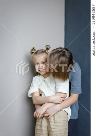 Laughing young sister and brother having fun and hugging indoor. Sibling children together portrait Laughing young sister and brother having fun and hugging indoor. Sibling children together portrait 129948687