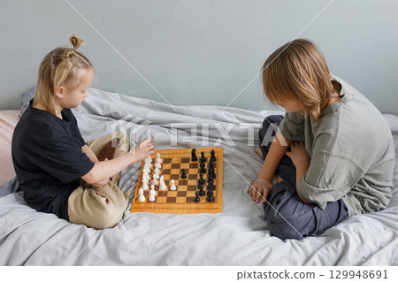 Intelligent little girl and young boy have a nice game. Sibling playing chess  129948691