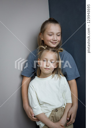 Cheerful sibling children having fun at home while standing against blue and white wall 129948695