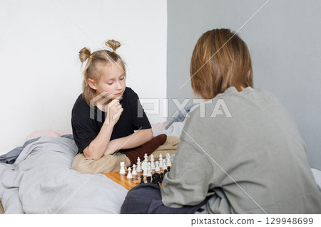 Clever kids, siblings or boy and girl together for learning games. Children playing chess 129948699
