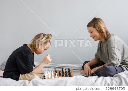 Smiling boy and girl playing chess board game while thinking of move with knowledge 129948705