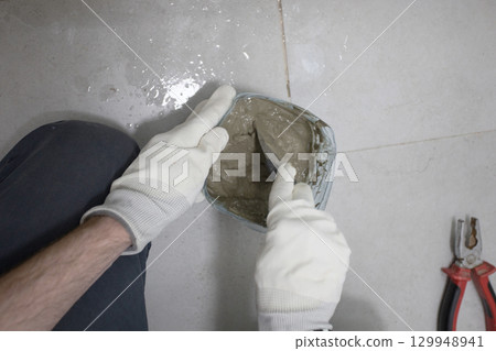 Handyman with cement glue for bathroom renovation work close up 129948941