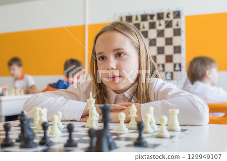 Pretty schoolgirl playing chess game in school classroom. Child girl on chess lesson strategy Pretty schoolgirl playing chess game in school classroom. Child girl on chess lesson strategy 129949107