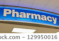 A vibrant pharmacy sign glows prominently against a clean, bright interior. 129950016