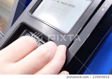 Close-up of a woman pressing a pin while paying credit card at self-checkout counter. 129950018