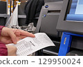 Close-up of a woman checking a receipt at self-check out counter inside Walmart store 129950024