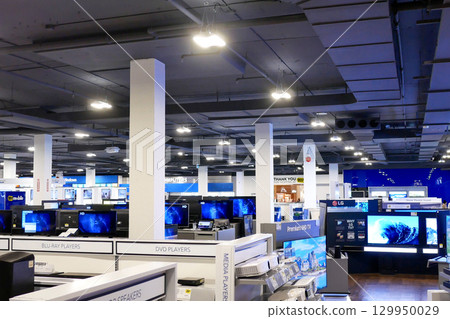 A wide-angle view of a modern electronics retail store, showcasing various displays of new TV. 129950029