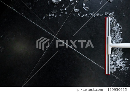 Broken glass cleanup on black tile floor with white and red broom Broken glass cleanup on black tile floor with white and red broom 129950635