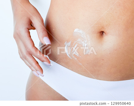 Female applying moisturizing cream on stomach close up Female applying moisturizing cream on stomach close up 129950640