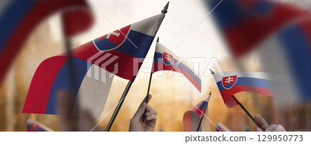 Slovakia flags in their hands on a blurred urban background 129950773