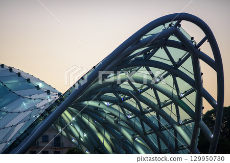 Peace bridge, steel and glass construction pedestrian bridge over Kura Mtkvari river in central Tbilisi, capital of Georgia 129950780