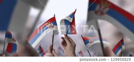 Serbia flags in their hands on a blurred urban background Serbia flags in their hands on a blurred urban background 129950829