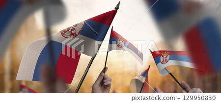 Serbia flags in their hands on a blurred urban background Serbia flags in their hands on a blurred urban background 129950830
