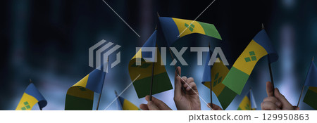 Saint Vincent flags in their hands on a blurred urban background 129950863
