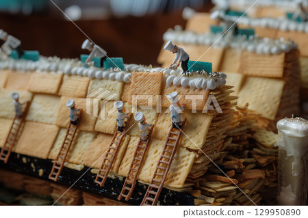 一位糕點師將一塊糖果貼在房子的牆上（立體模型） 129950890