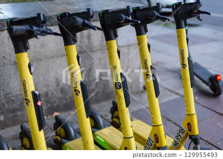 Row of yellow Yandex electric scooters parked in a city street in Tbilisi, Georgia 129955493
