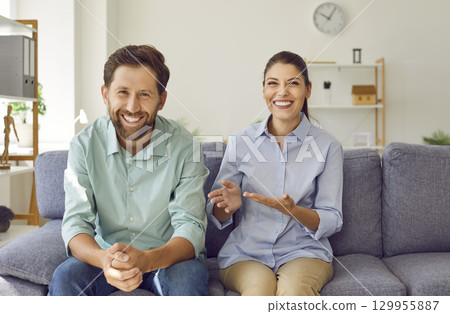 Happy couple looking and smiling at camera making video call chatting with friends online. Happy couple looking and smiling at camera making video call chatting with friends online. 129955887