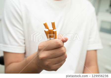 Asian man holding cigarette in hand, no smoking. Asian man holding cigarette in hand, no smoking. 129956236