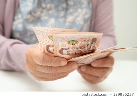 Retired elderly woman counting coins money and worry about monthly expenses and treatment fee payment. 129956237