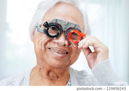 Optometrist checking Asian elderly woman ophthalmic vision eye test and using optical trial frame. Optometrist checking Asian elderly woman ophthalmic vision eye test and using optical trial frame. 129956243